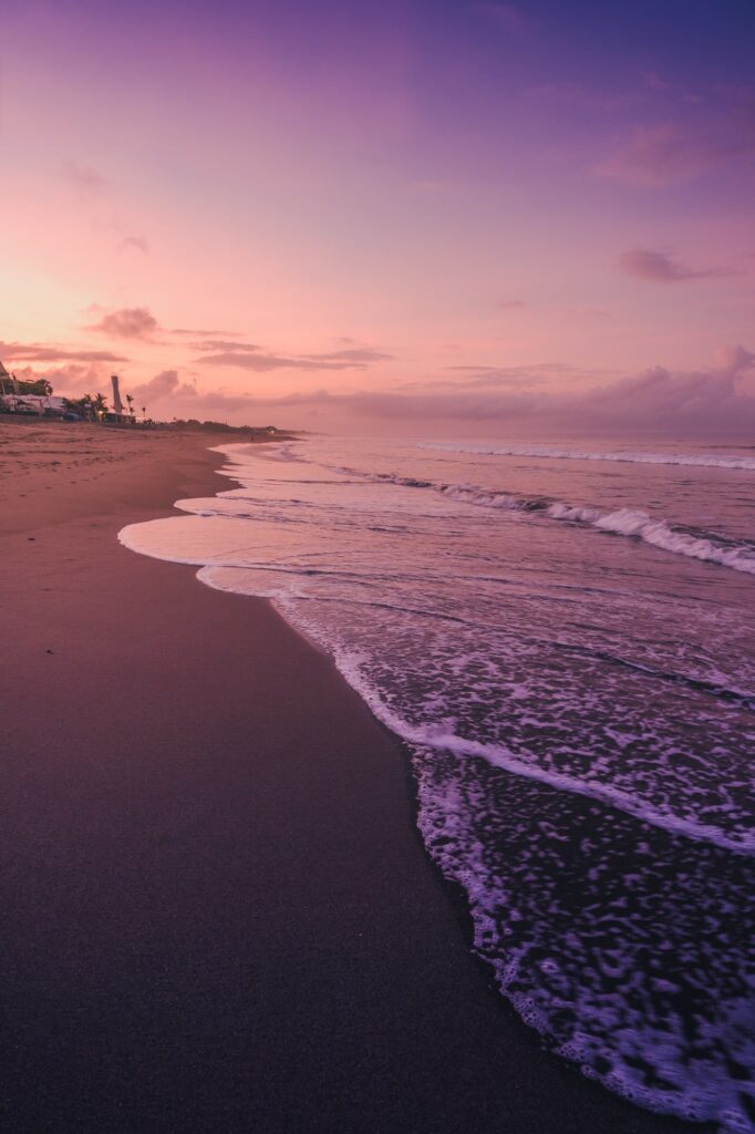 Vertical shot of the sea waves under the beautiful purple sky captured in Canggu, Bali
